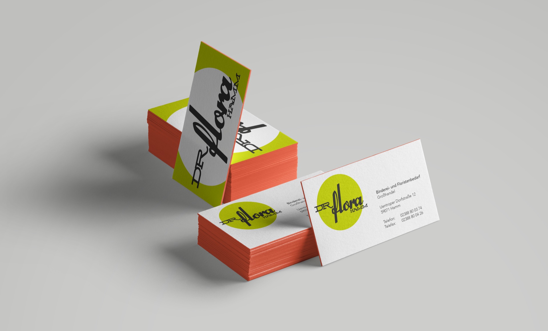 Mockup der DR FLORA HAMM Visitenkarten mit schwarzem Schriftlogo, gelbgrünen Kreisflächen und korallroten Kanten