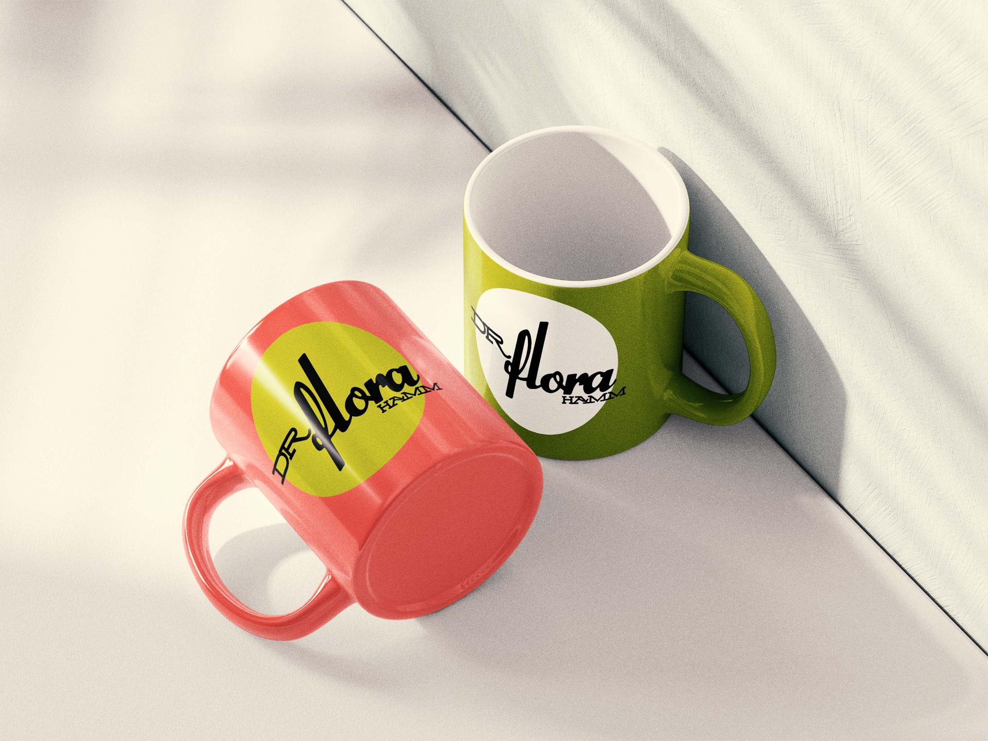 Mockup einer korallroten und einer gelbgrünen Tasse mit DR FLORA HAMM Schriftlogo auf Kreisflächen